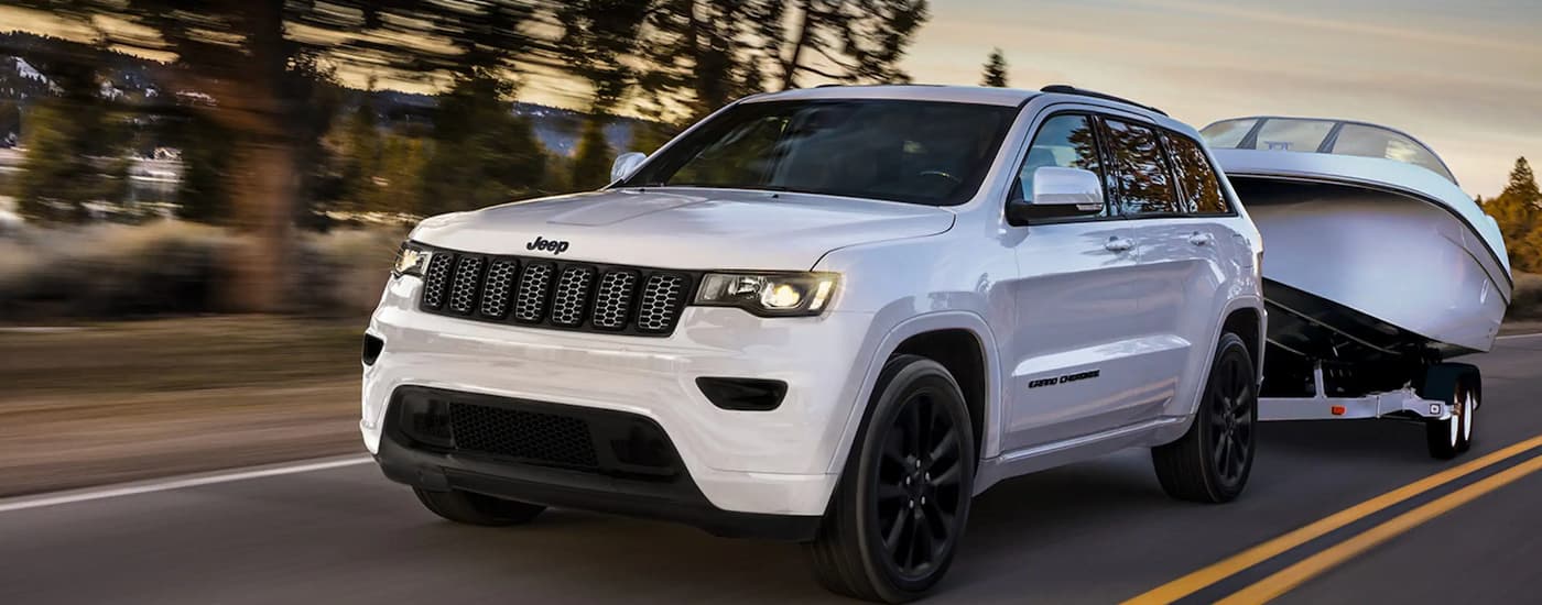 Used%20Car%20Dealer%20Near%20Pembroke%20Pines%20-%202022%20Jeep%20Grand%20Cherokee%20WK%20-%20White%20Towing.jpg White 2022 Jeep Grand Cherokee towing a boat on a winding road