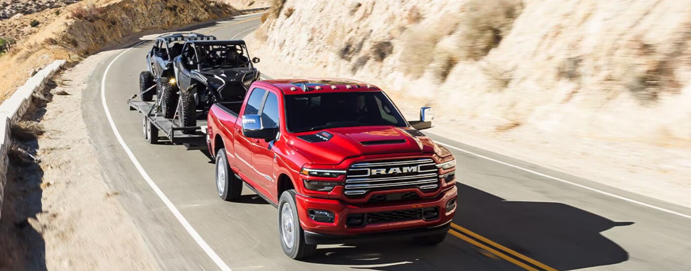 2026%20Ram%202500%20-%20towing.png Red 2026 Ram 2500 towing a side-by-side down the road