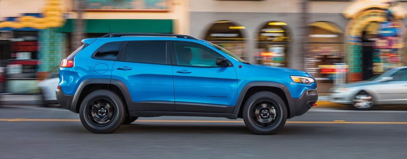 wlp%20-%202023%20Jeep%20Cherokee%20Trailhawk%20%20-%20Used%20Car%20Dealer%20Near%20Key%20Biscayne%20%20-%20Side.jpg A blue 2023 Jeep Cherokee Trailhawk driving on a city street