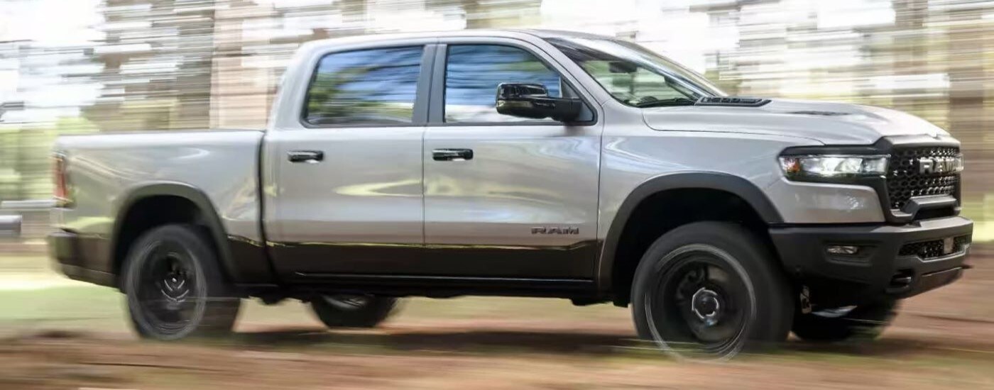 2025%20Ram%201500%20-%20Blur%20(1).jpg Silver 2025 Ram 1500 driving down a trail