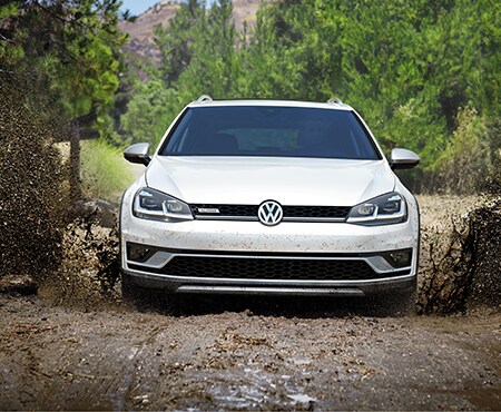 Front View of White Volkswagen Golf Alltrack driving through a mud puddle