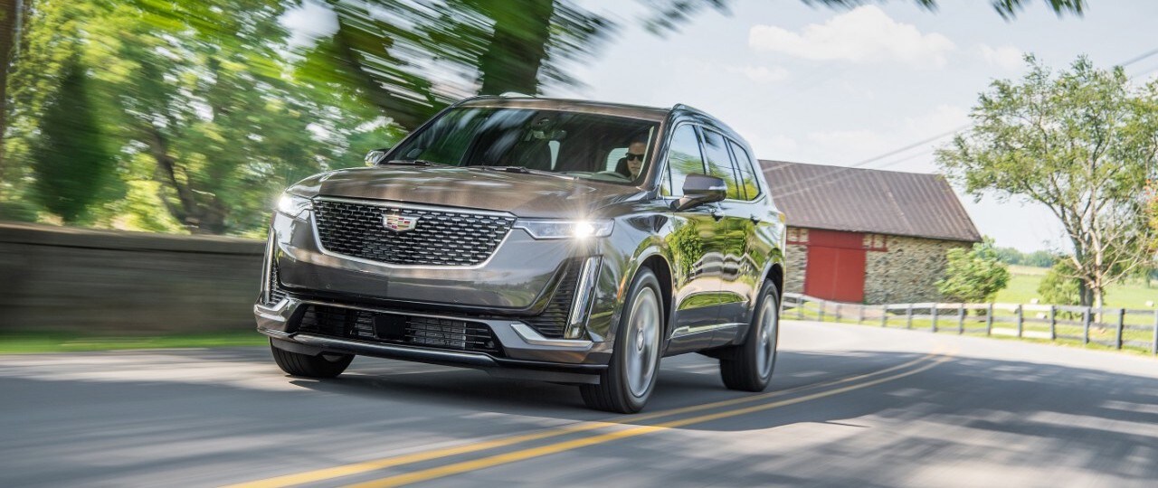 Cadillac Laval - VUS Cadillac d'occasion - XT6 Premium Luxury 2020 - 0,3.jpg Cadillac XT6 Premium Luxury 2020 gris conduisant sur l'autoroute en campagne avec ses phares avant allumés