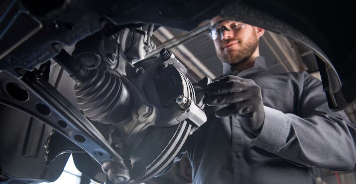 A certified Cadillac technician examines the brake fitting on a vehicle A certified Cadillac technician examines the brake fitting on a vehicle