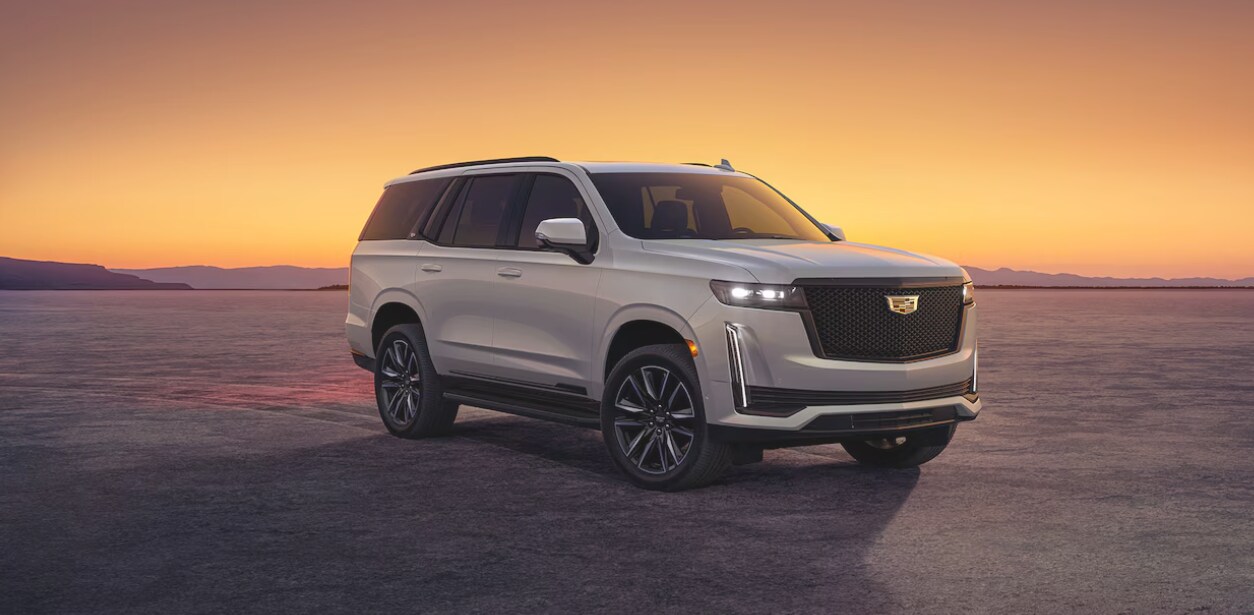 A white 2024 Cadillac Escalade at sunset on a salt flat A white 2024 Cadillac Escalade at sunset on a salt flat