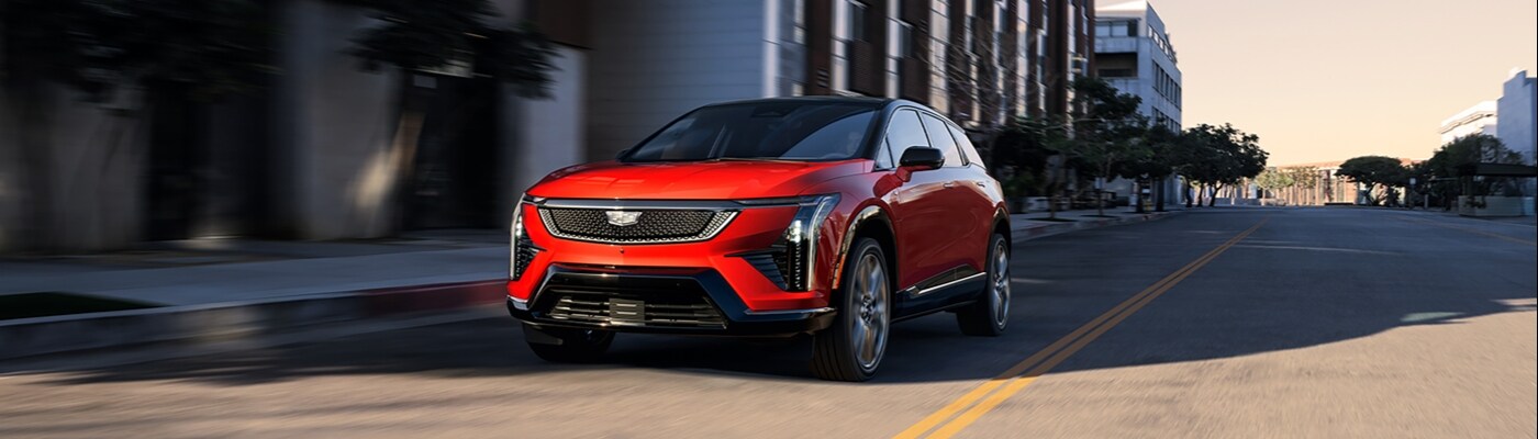 A red Cadillac OPTIQ SUV parked along a city street new CADILLAC LYRIQ