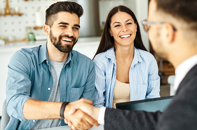 A couple shaking hands with a salesperson