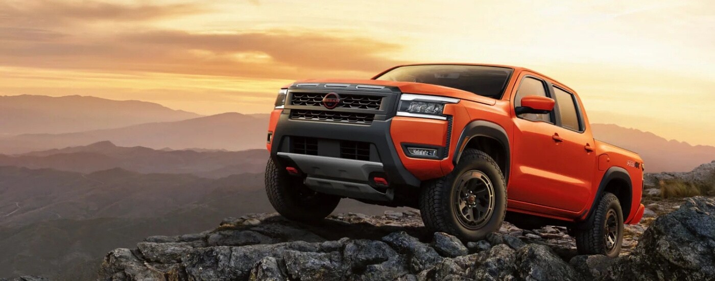 An orange 2025 Nissan Frontier for sale near Grand Bay from the front.