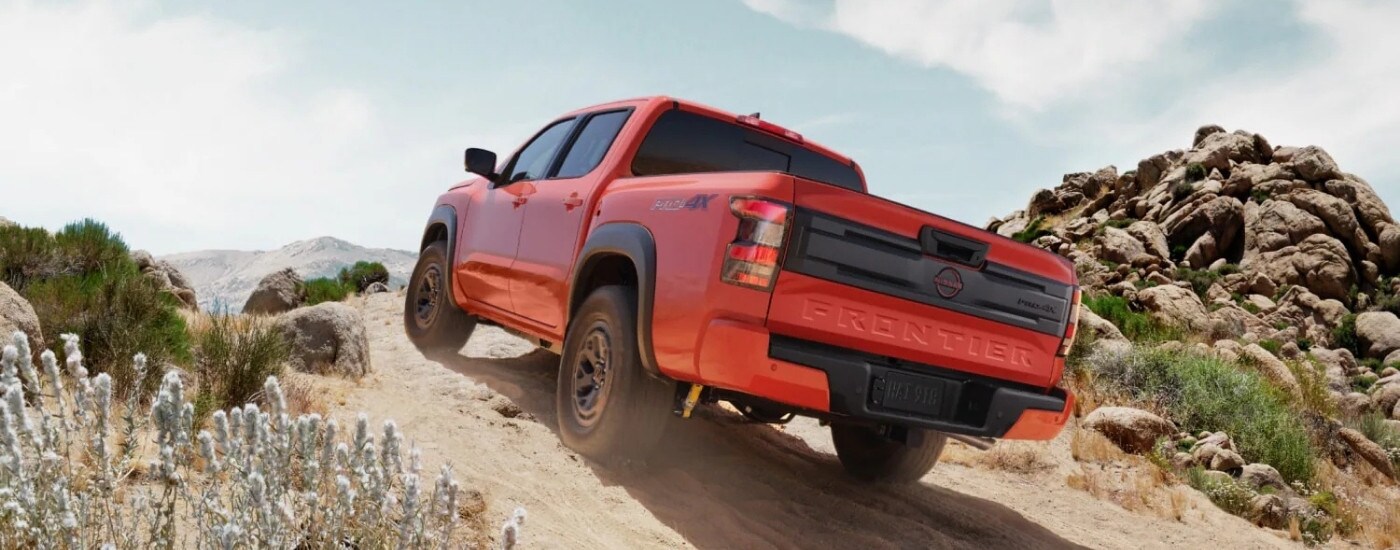 An orange 2025 Nissan Frontier from the rear at an angle.