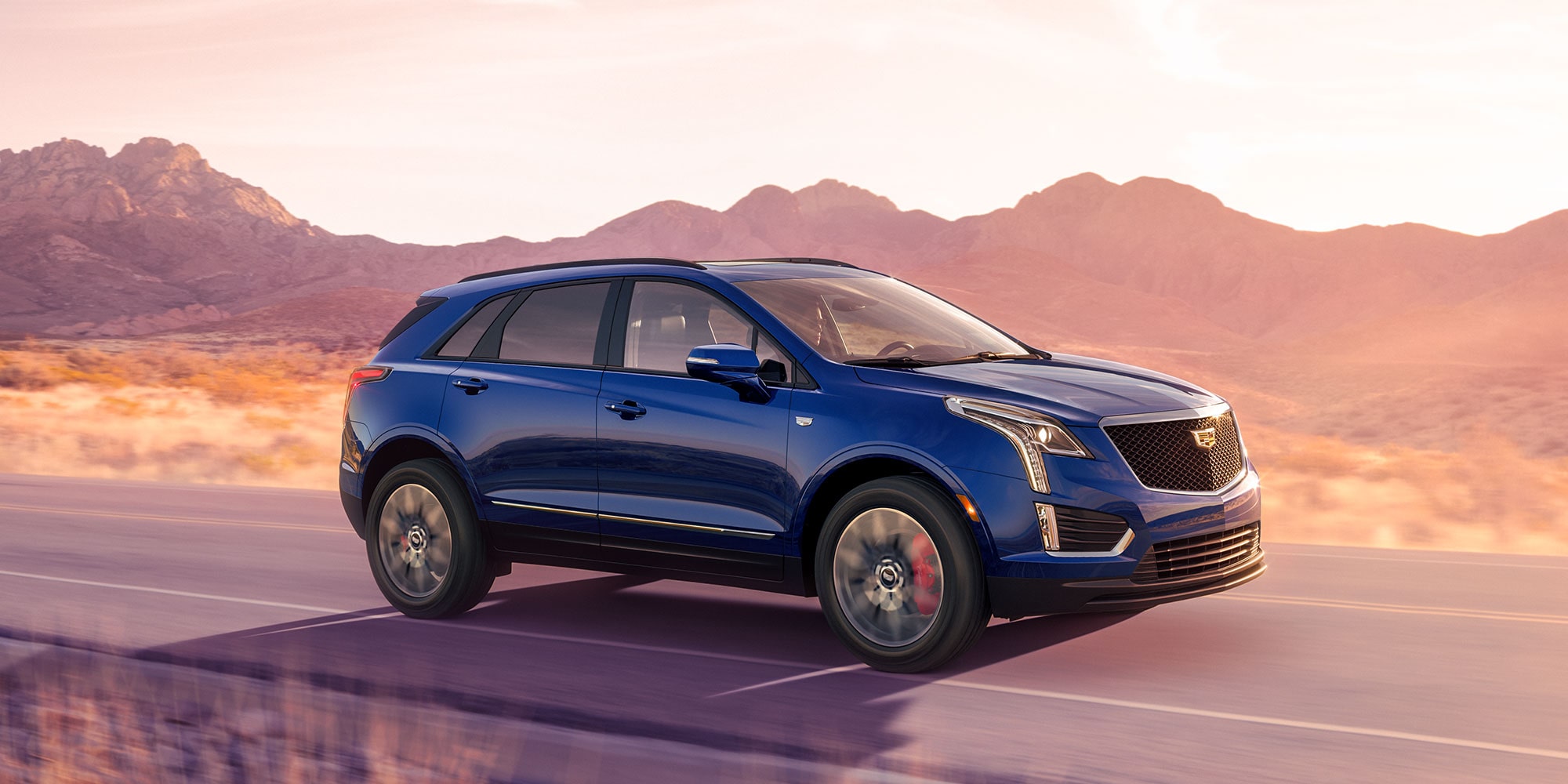 A blue Cadillac XT5 driving down the road A blue Cadillac XT5 driving down the road