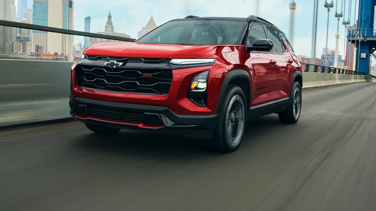A red Chevrolet Equinox driving over a bridge to a city A red Chevrolet Equinox driving over a bridge to a city