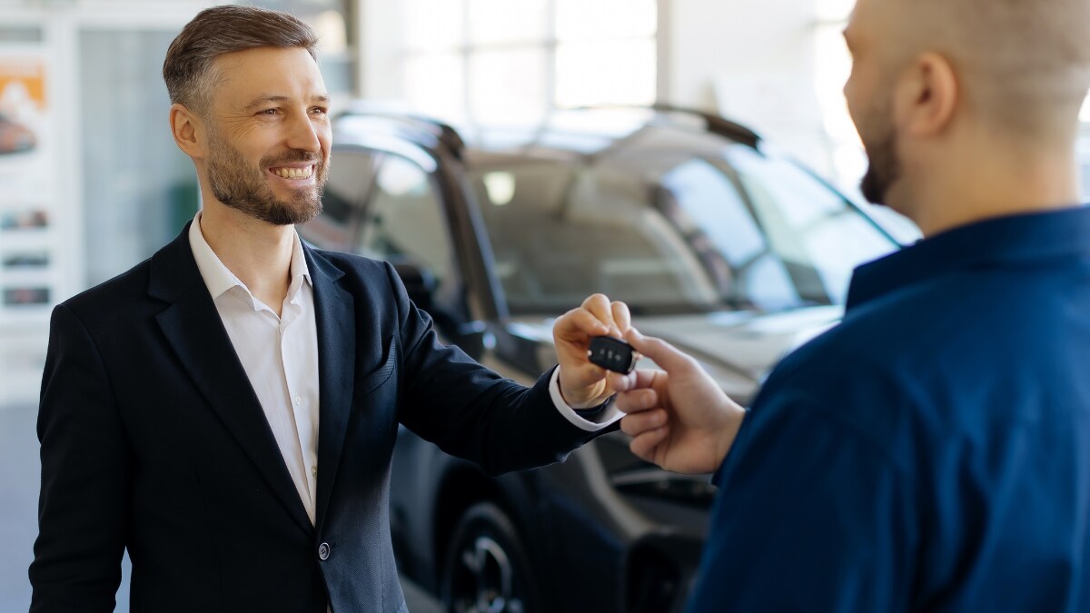 A man taking his car keys back from a technician in a service center. A man taking his car keys back from a technician in a service center.