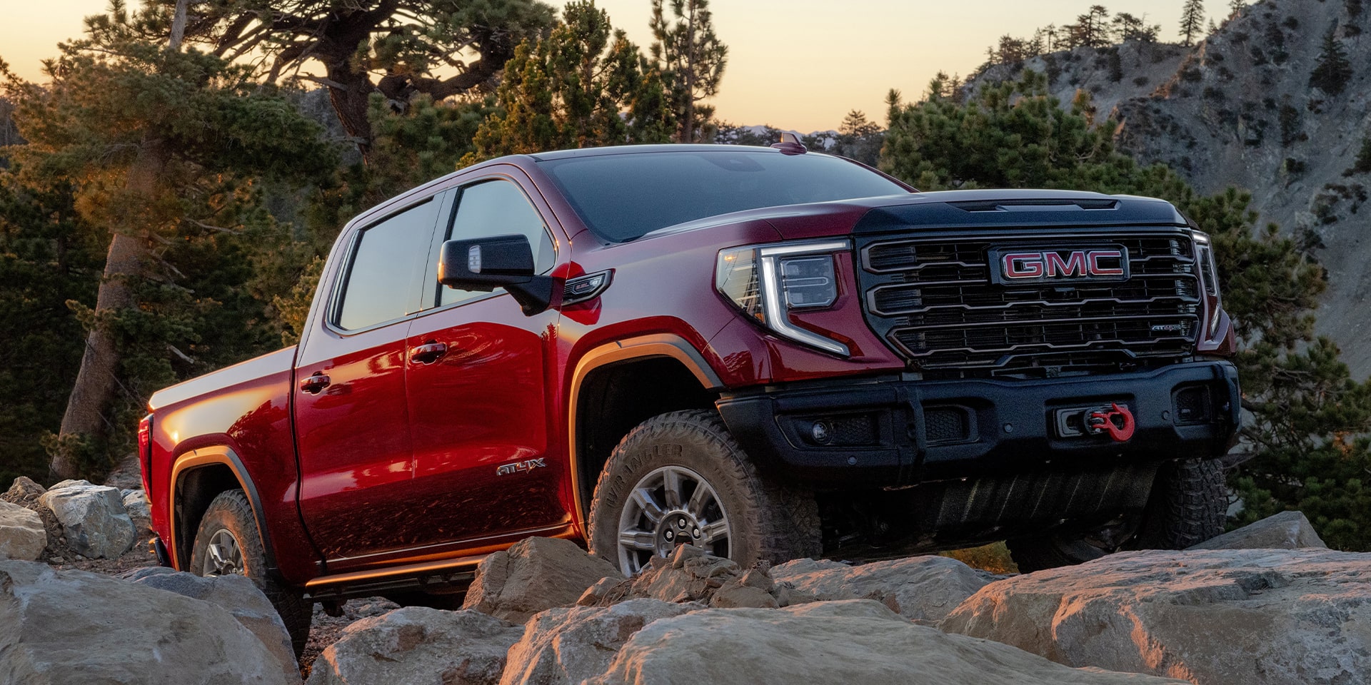 A red GMC Sierra 1500 driving over rocks A red GMC Sierra 1500 driving over rocks