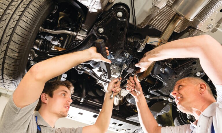 Car Mechanic working under raised car