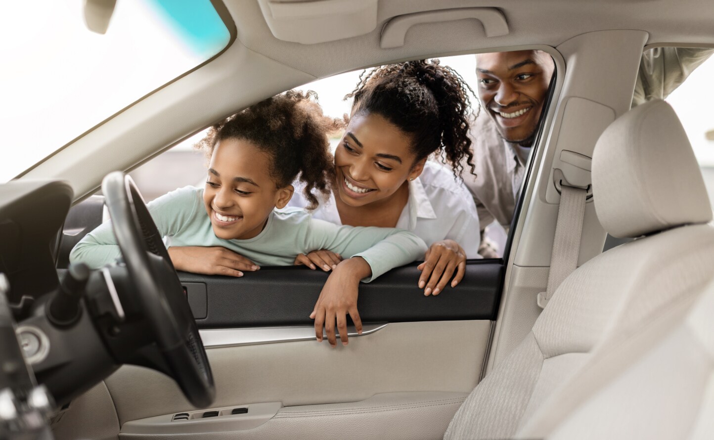Smiling family looking inside of their used vehicle