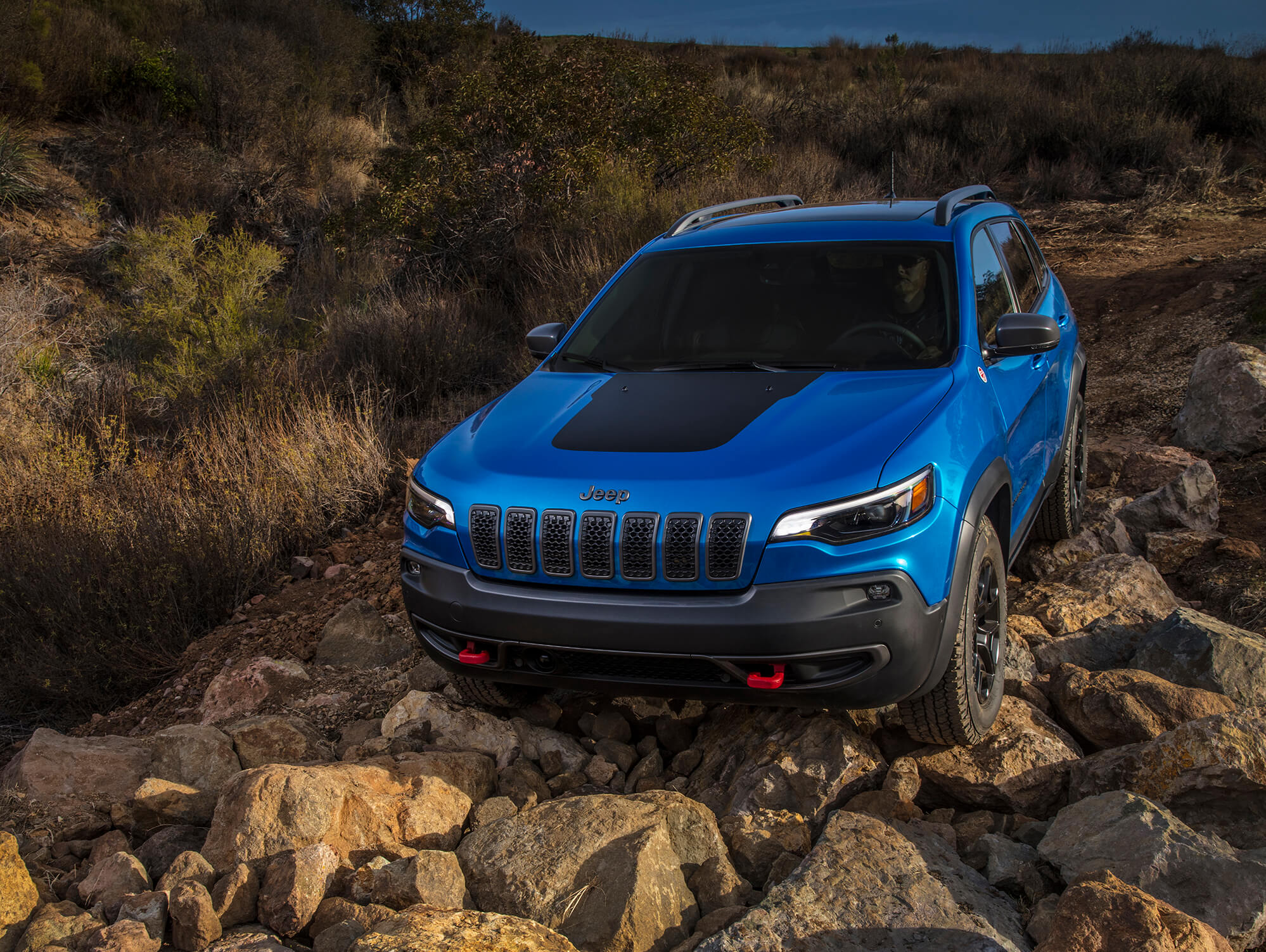 Le Jeep Cherokee Trailhawk 2021 bleu parcourant les rochers