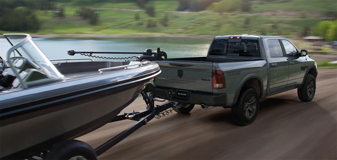Le RAM 1500 Classic 2021 remorquant un bateau sur la route au bord d'un lac