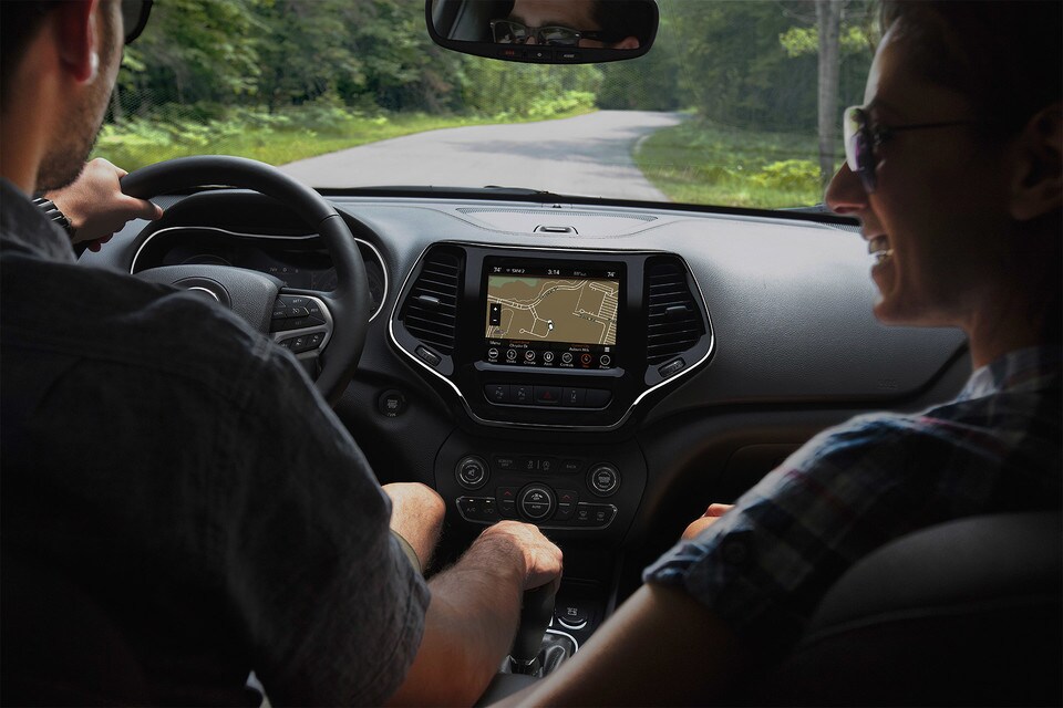 Couple Driving 2020 Jeep Cherokee and pointing at console Couple Driving 2020 Jeep Cherokee and pointing at console
