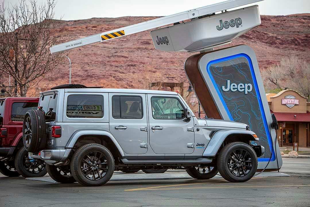 vue latérale du Jeep Wrangler 4xe 2021 stationné proche d'une borne de recharge