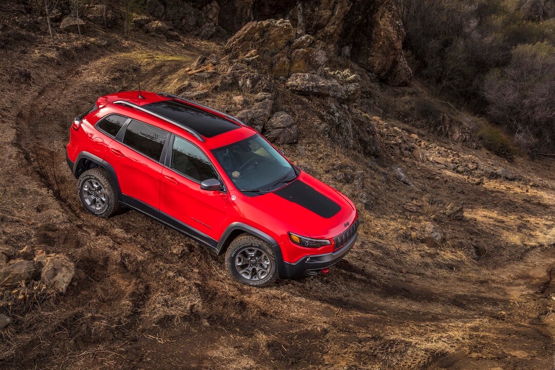 Un VUS compact Jeep Cherokee Trailhawk 2019 rouge sur une piste en nature