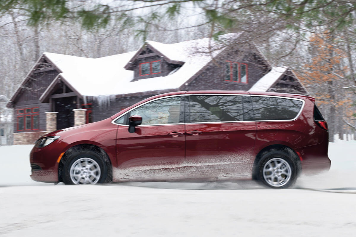 Vue latérale d'une mini-fourgonnette Chrysler Grand Caravan 2022 roulant sur une route enneigée