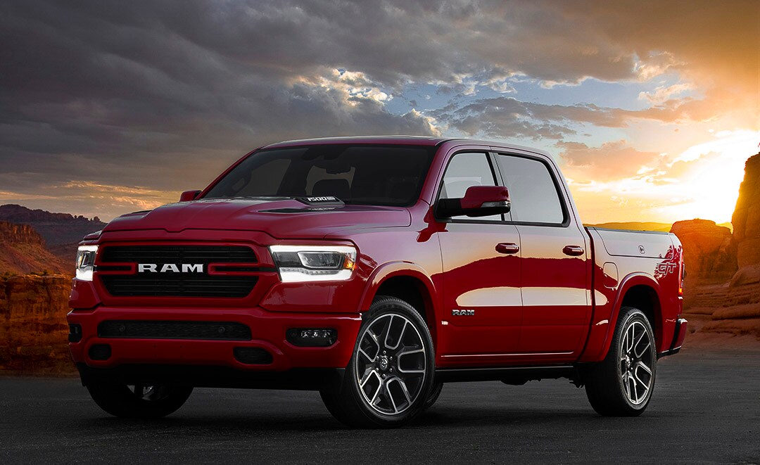 Vue 3/4 avant du RAM 1500 Laramie G/T 2022 rouge garé non loin d'un canyon au crépuscule