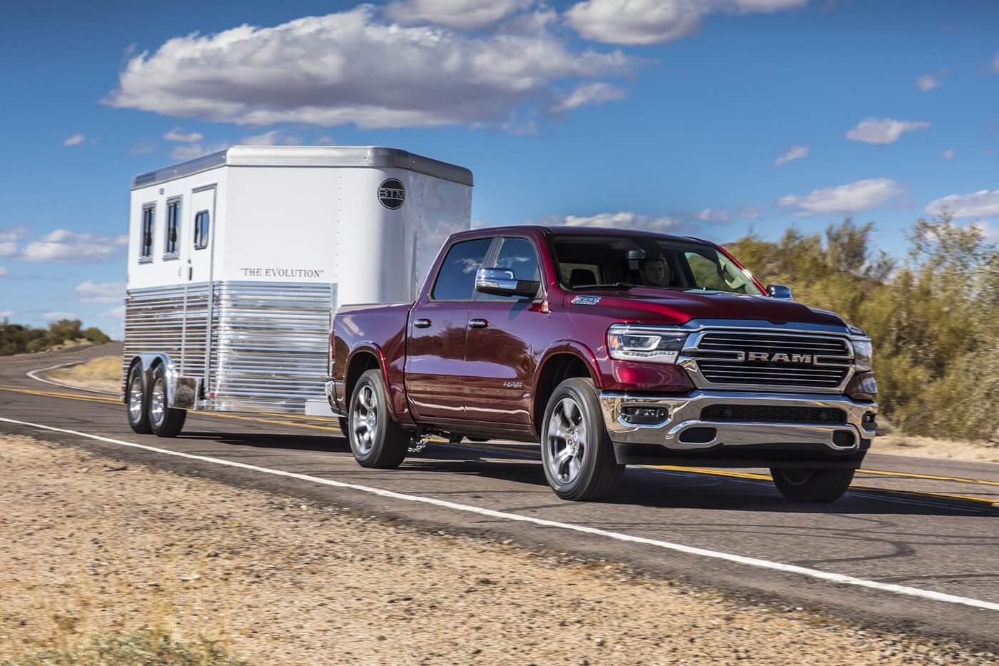Vue 3/4 avant d'un RAM 1500 Laramie 2022 rouge remorquant une mini-roulotte sur une route