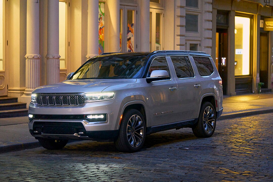 Vue 3/4 avant d'un Jeep Grand Wagoneer 2022 zénith argenté garé au bord d'un trottoir sur un pavé