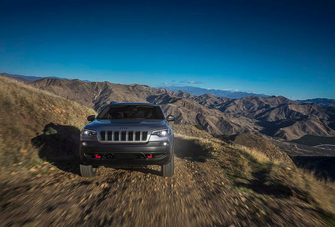 Facing a silver Jeep Cherokee 2021 Trailhawk argent près du sommet d'une montagne