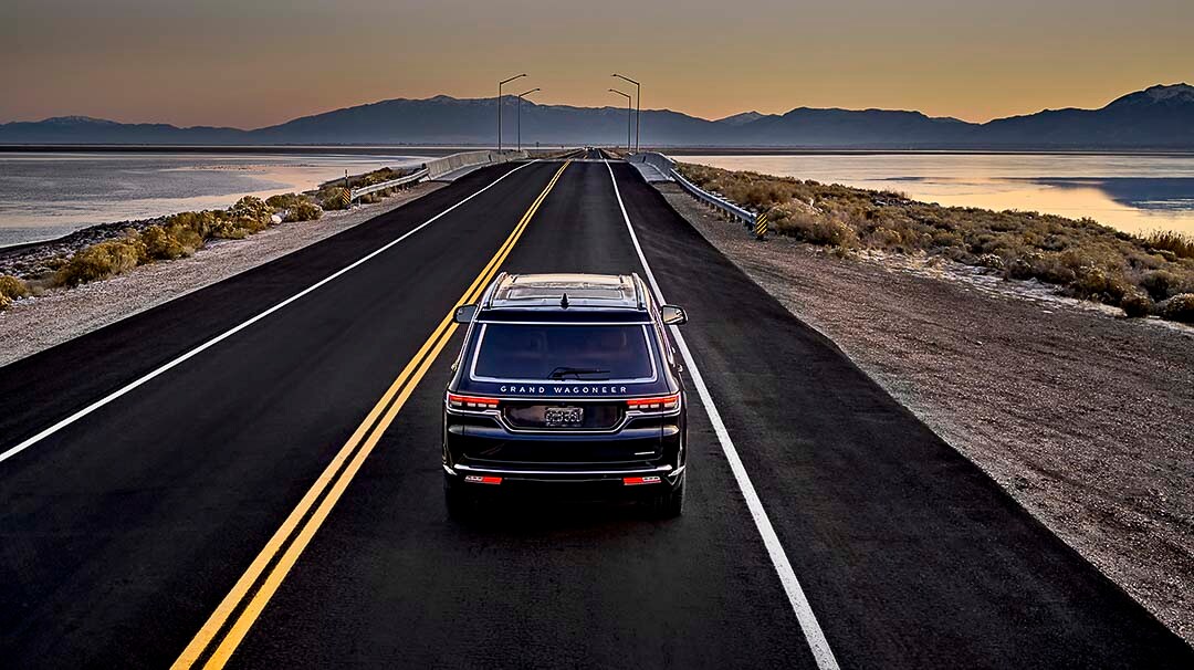 Vue arrière du Jeep Grand Wagoneer 2022 roulant sur la route en direction des montagnes