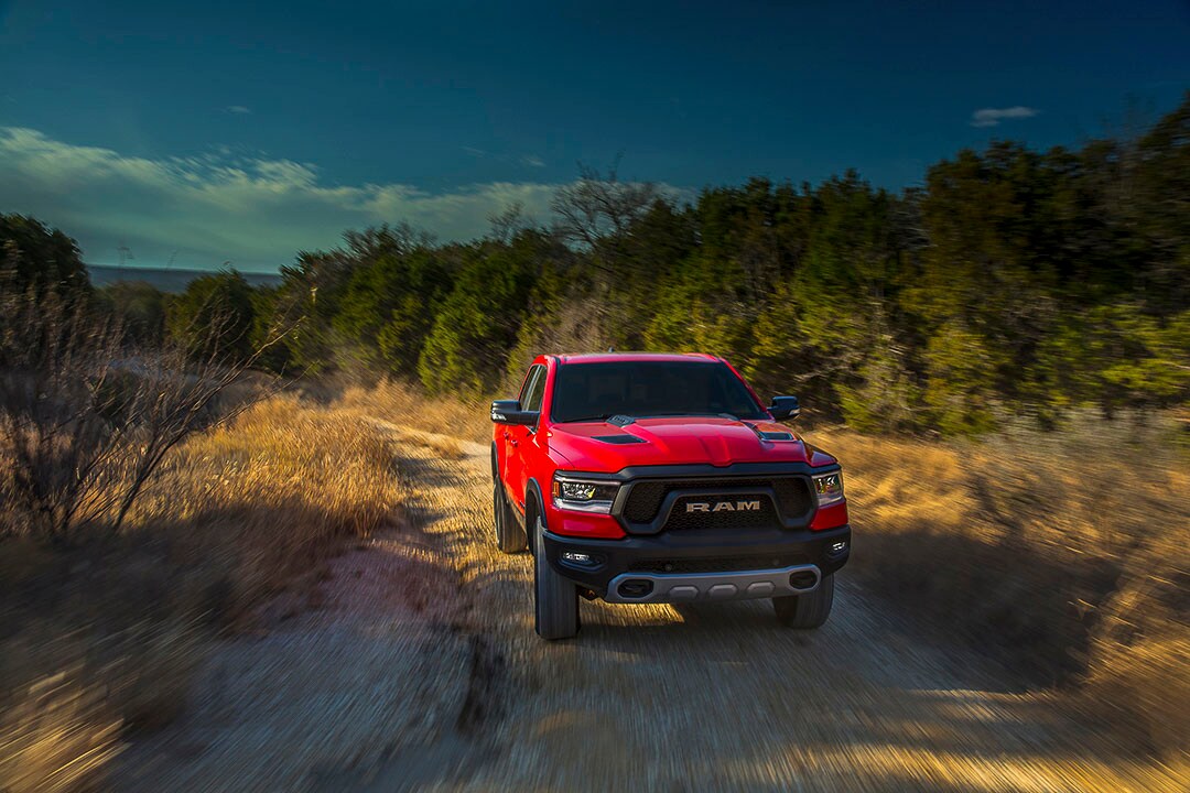 Le RAM 1500 Rebel 2022 rouge roulant sur un chemin de terre battue en forêt