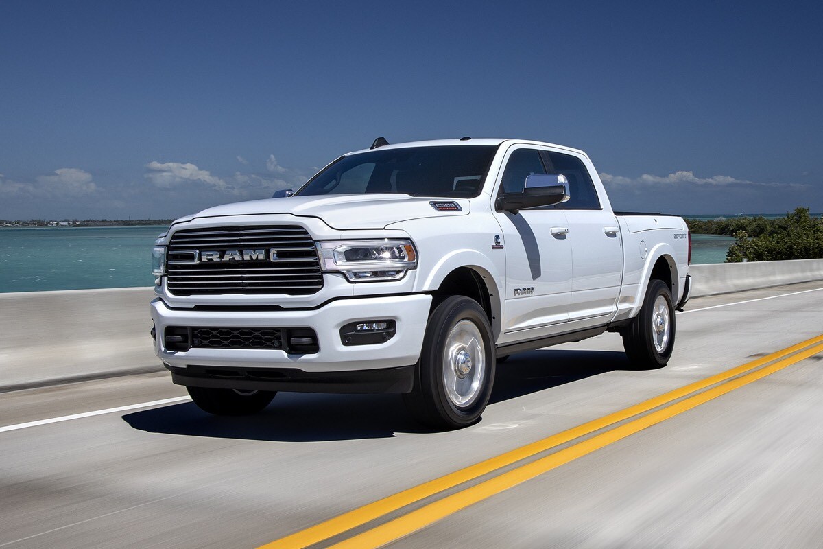 Vue 3/4 du RAM 2500 2022 blanc roulant sur une route au bord de l'eau