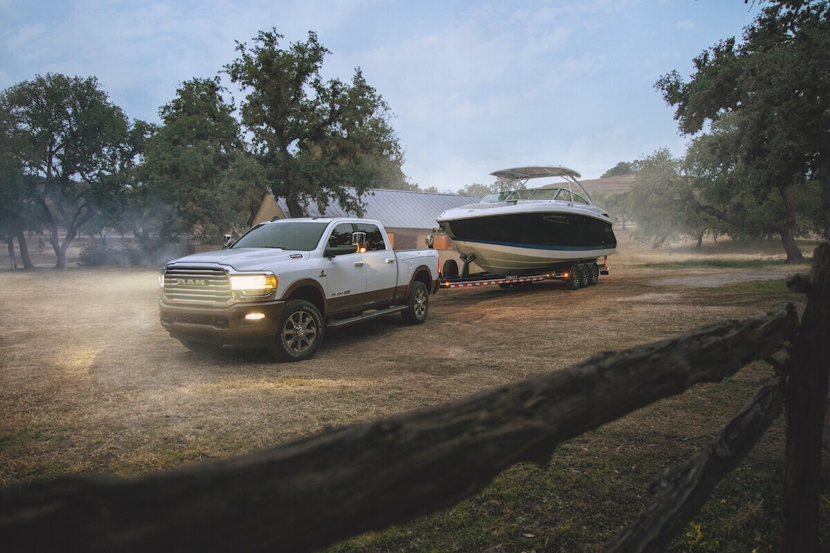 Le RAM Power Wagon 2021 à cabine multiplace 2021 contenant un bateau sur sa remorque et garée sur un terrain