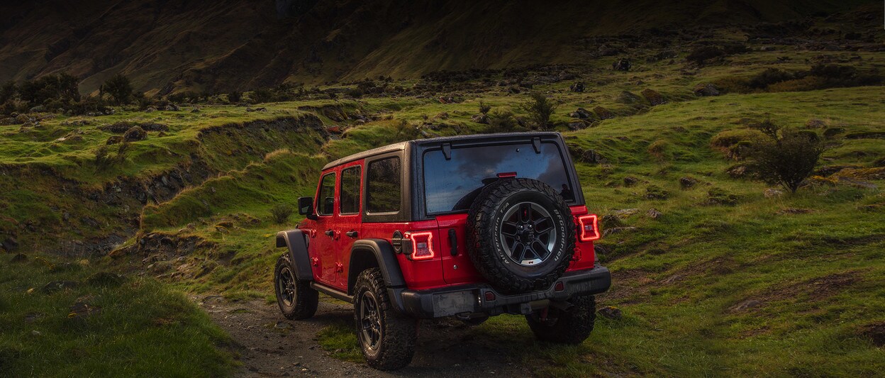 Red 2020 Jeep Wrangler driving off-road in the rain Red 2020 Jeep Wrangler driving off-road in the rain