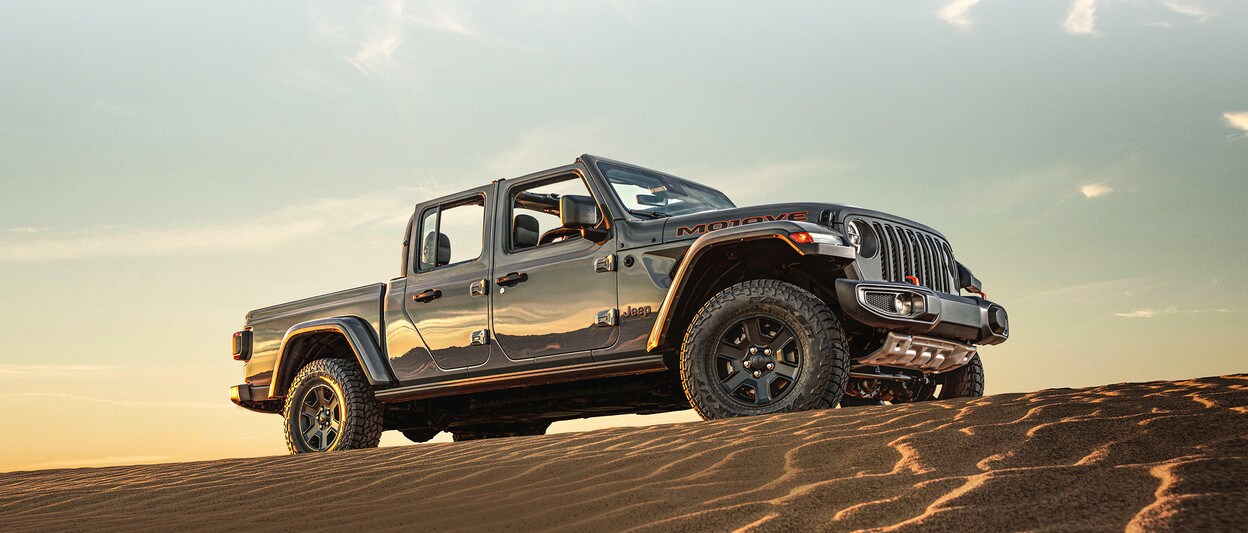 2020 Jeep Gladiator parked on top of sand hill in a desert 2020 Jeep Gladiator parked on top of sand hill in a desert