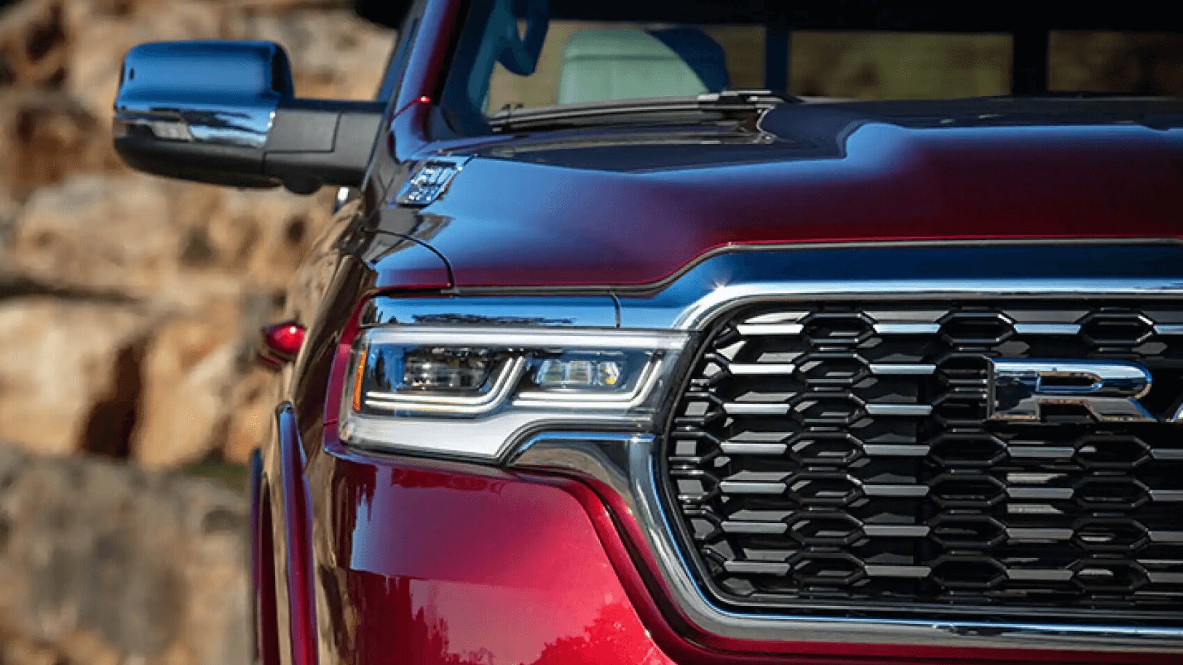 Learn about the specs & features of the 2025 Ram 1500 Exterior of a red Ram 1500 showing redesigned LED headlight and new front grille design