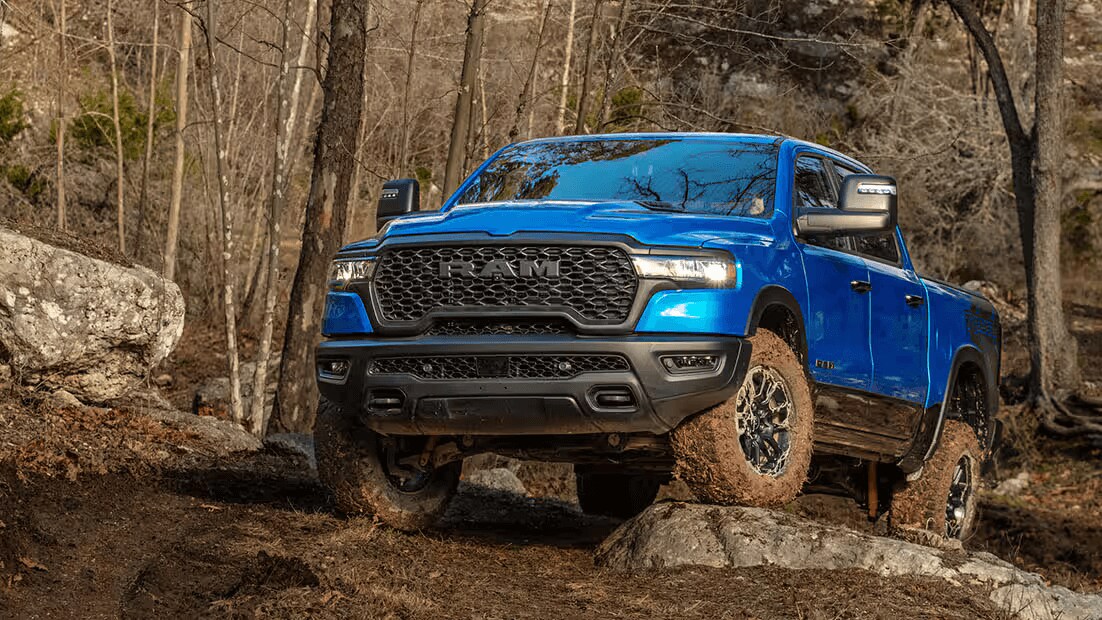 Learn about the specs & features of the 2025 Ram 1500 Blue Ram 1500 driving over a rock-covered forest trail