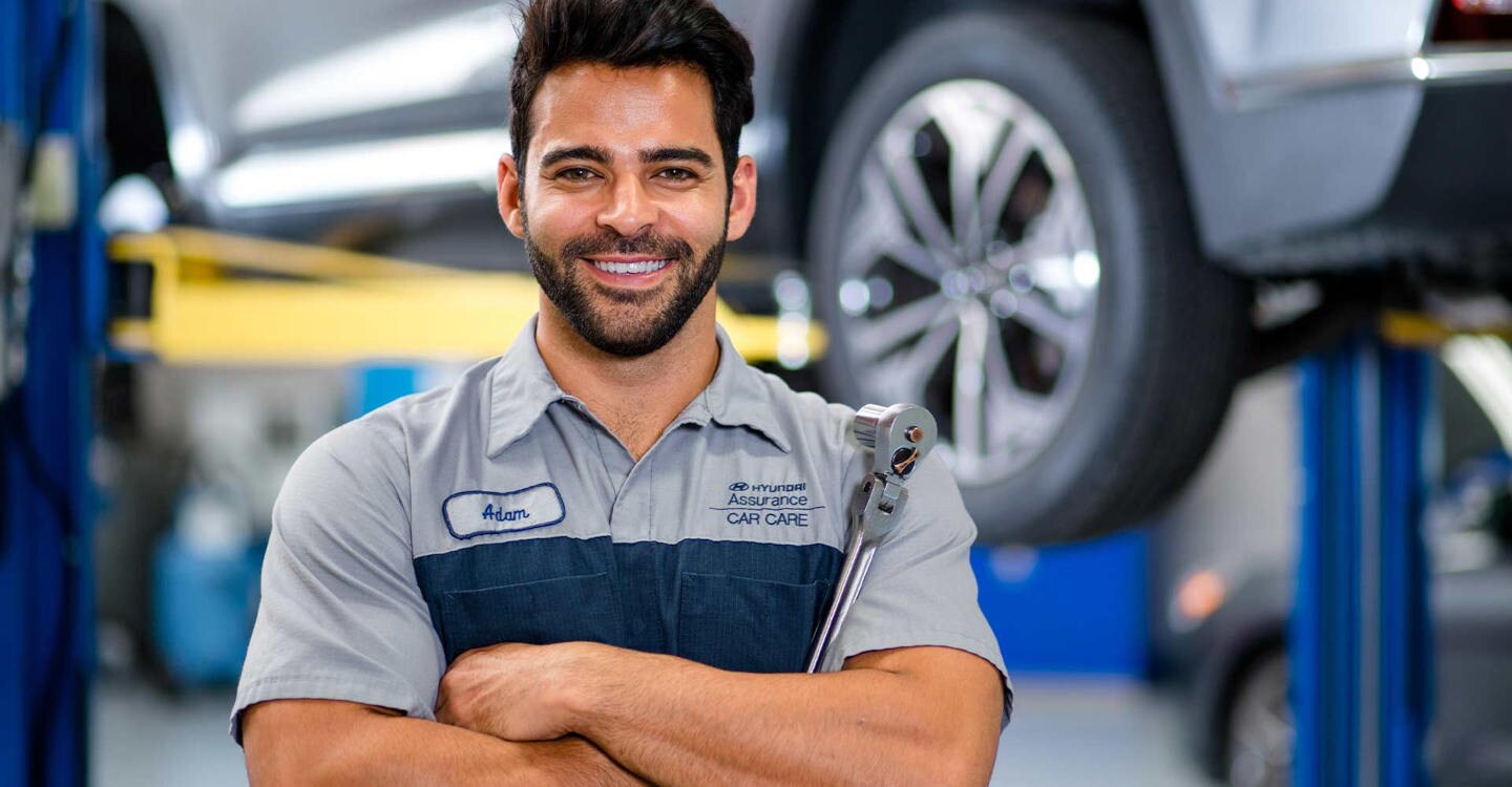 Hyundai mechanic smiling in front of a car lift