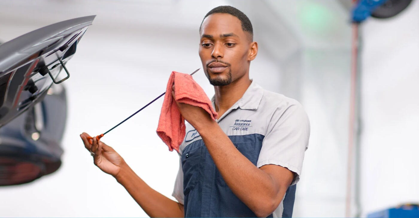 Hyundai Mechanic checking oil level with a dipstick