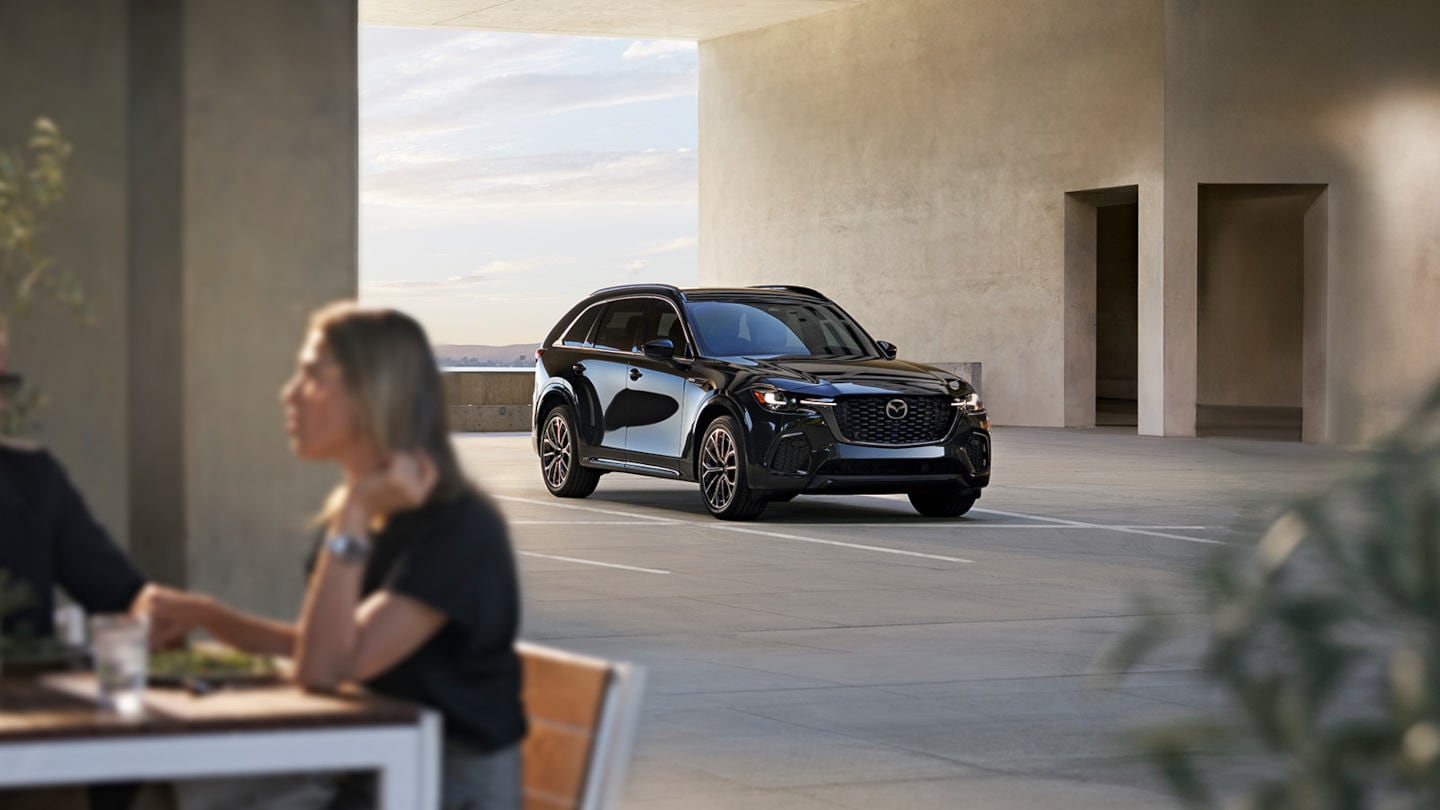 2025 Mazda CX-70 parked behind a lady having a meal