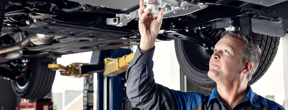 Man changing oil filter under an Engine