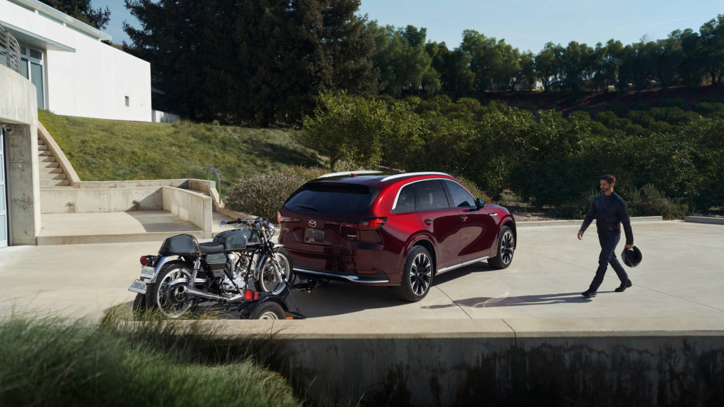 2025 Mazda CX-90 parked in a driveway with a motorcycle trailer