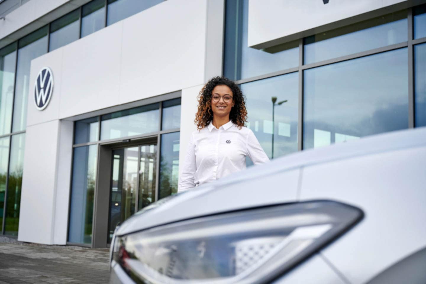 finance women stands between a Volkswagen dealership and new car