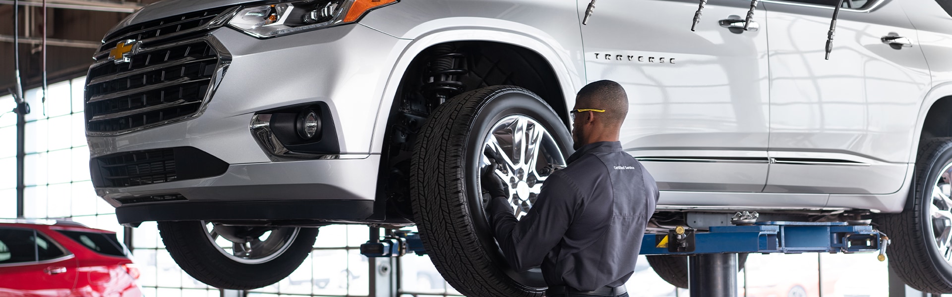 C3 Main Benefits of Using OEM parts for your vehicle at Chevrolet of New Bern | Chevrolet service technician changing tire on silver 2020 Chevrolet Traverse