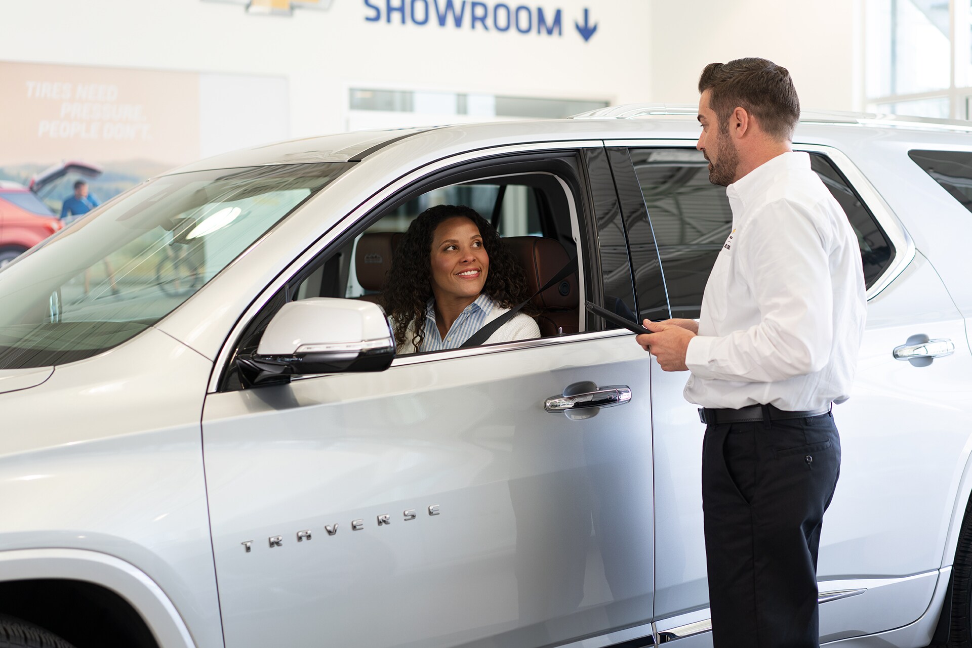 Chevrolet of New Bern is a Car Dealership in New Bern near Bridgeton NC | Chevrolet Service Advisor assisting customer driving White 2020 Chevrolet Traverse in Chevrolet Service Center