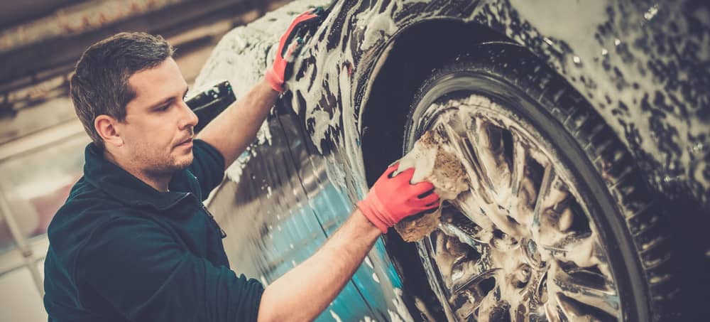 man washes wheel of vehicle