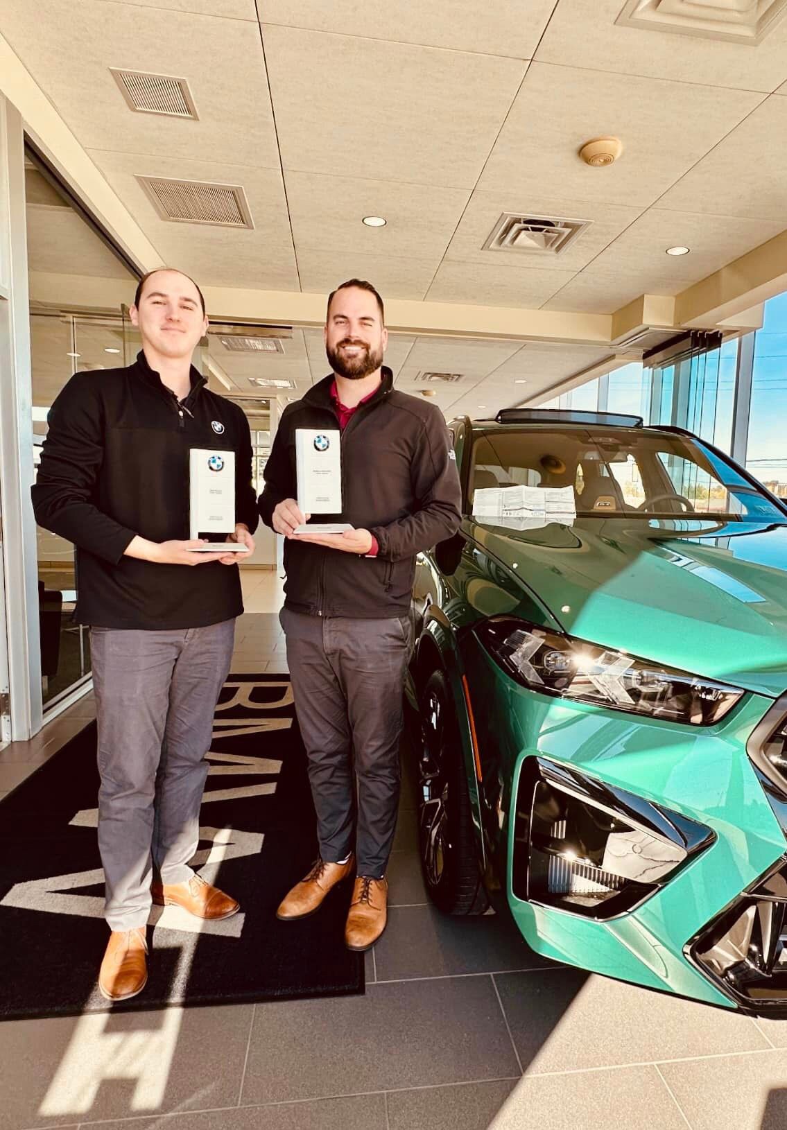 395230662_763963572409546_6846399367993202031_n.jpg two men holding awards next to a green car at a bmw dealership in york, pa
