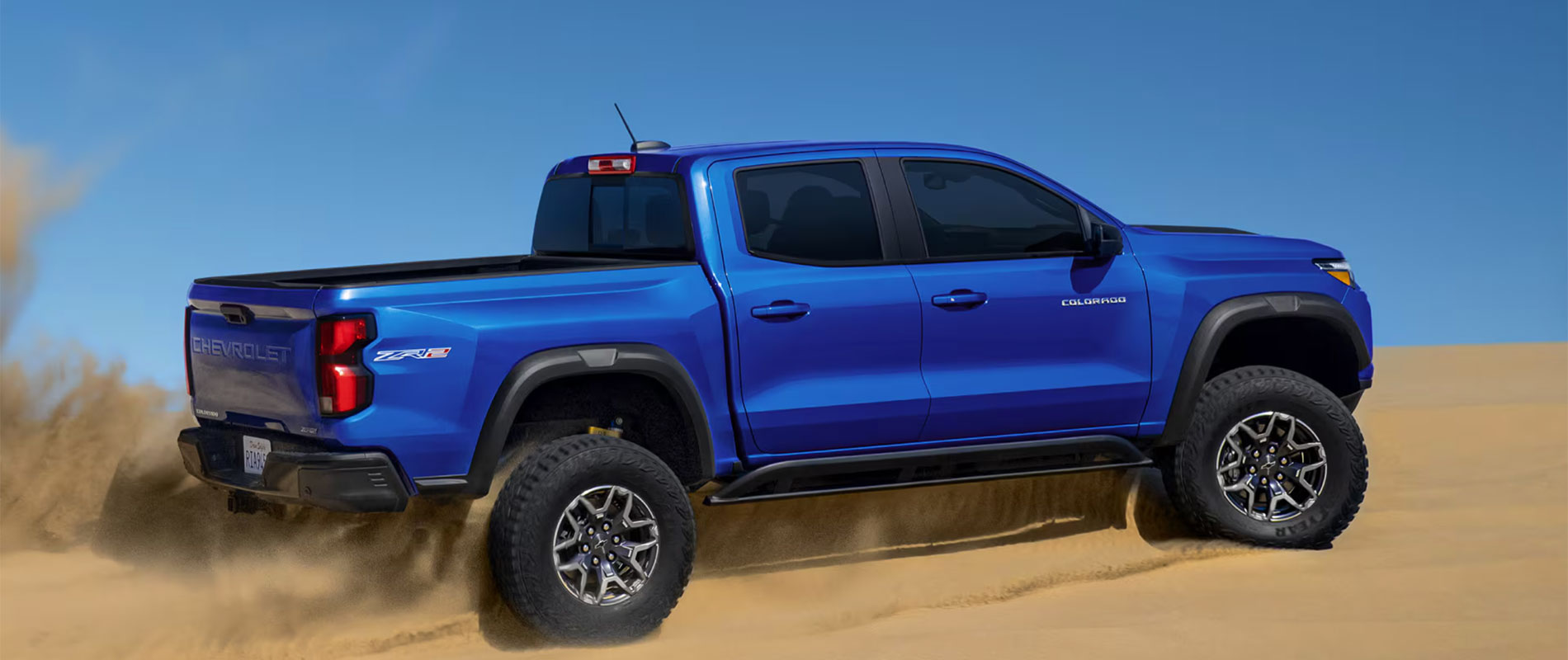 2026 Chevrolet Colorado Trim Comparison 2026 Chevy Colorado driving up a sand dune