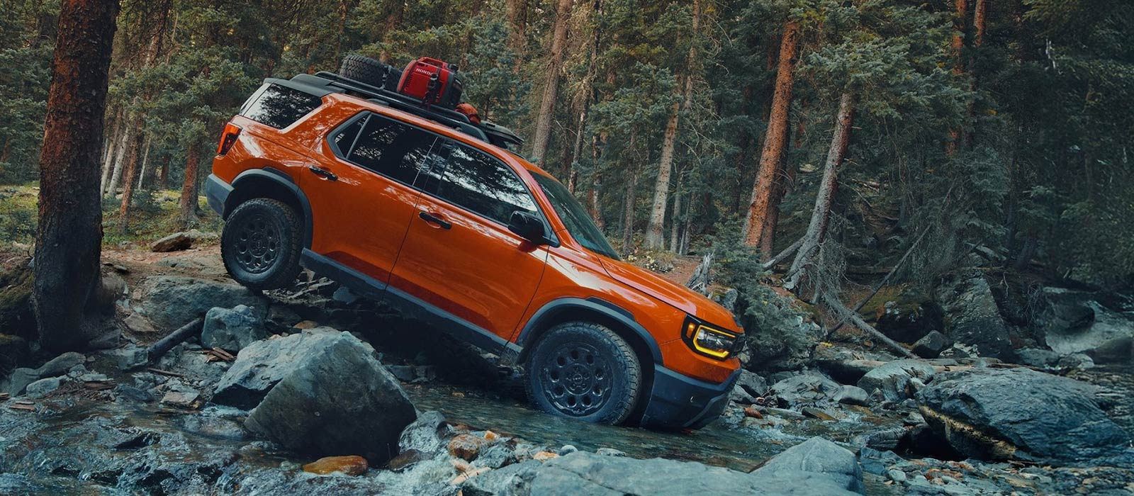 2026 Honda Passport Trim Comparison 2026 Honda Passport driving on rocky hill in woods