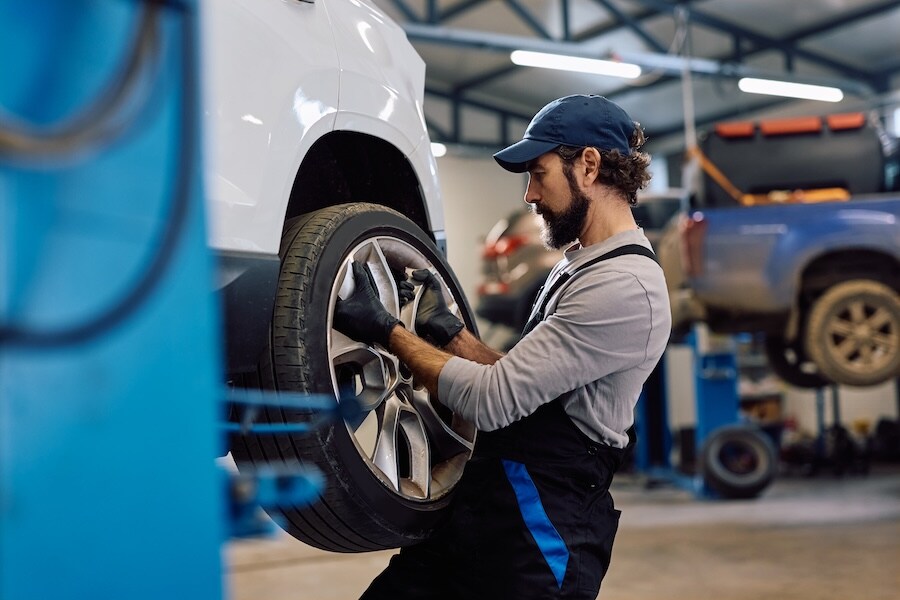 A service technician changing the tire of a vehicle in a service department