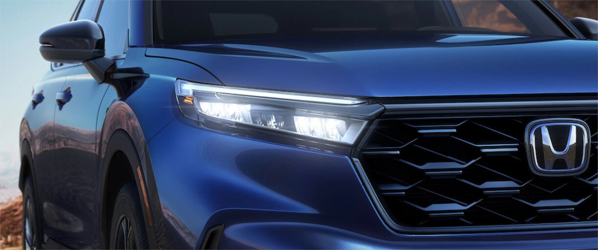 A closeup of the headlights and grill of a blue 2026 Honda CR-V SUV A closeup of the headlights and grill of a blue 2026 Honda CR-V SUV